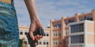 Person holding gun near school building outside