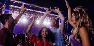 Group of young adults dancing and enjoying a music festival under colorful lights