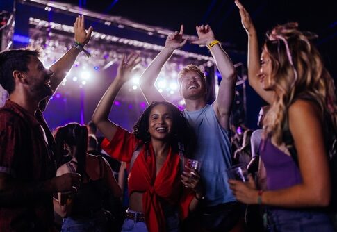Group of young adults dancing and enjoying a music festival under colorful lights