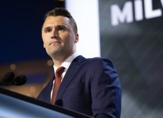 A man in a suit speaking at a podium during a conference
