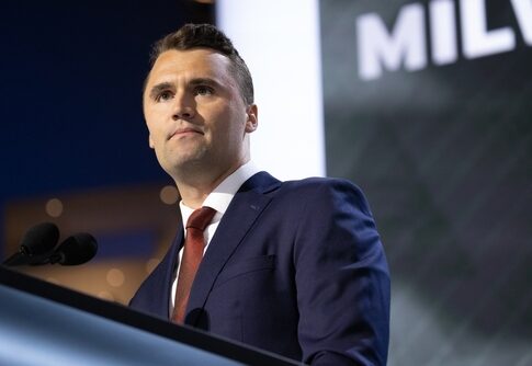 A man in a suit speaking at a podium during a conference