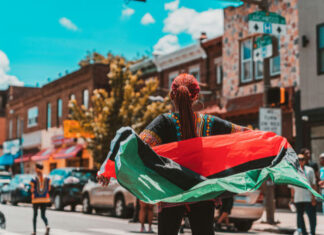 Person holding a flag on a busy street.
