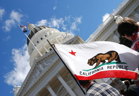 California state flag in front of Sacramento Capitol building.