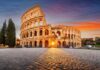 The Colosseum in Rome at sunset with a glowing sun in the background