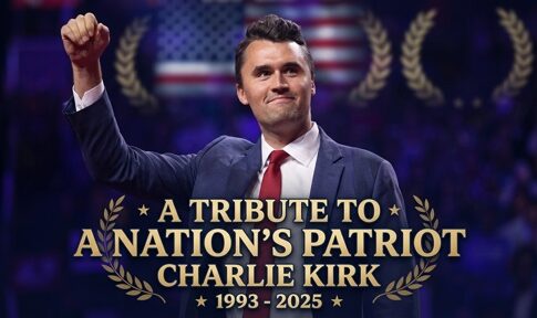A man raising his fist in a tribute event for Charlie Kirk