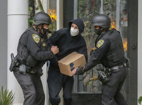 Police arresting person holding a box.