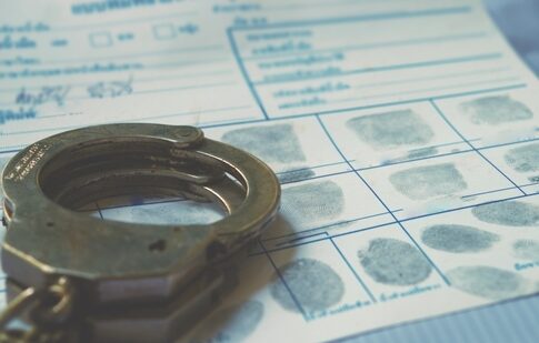 Handcuffs resting on a fingerprint card with inked fingerprints