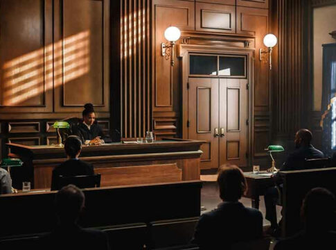 Judge presiding over courtroom with people seated inside.