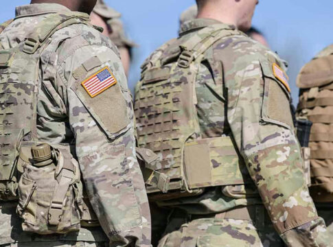 Soldiers in camouflage uniforms with American flags on sleeves.