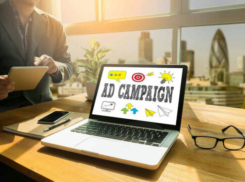 Laptop displaying Ad Campaign on desk in bright office.