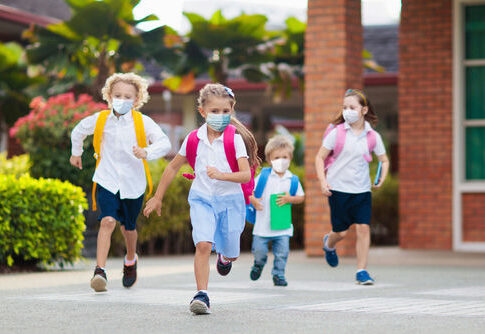 Children wearing masks running outside a school