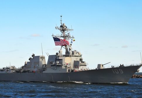 naval destroyer with flags sailing on open water