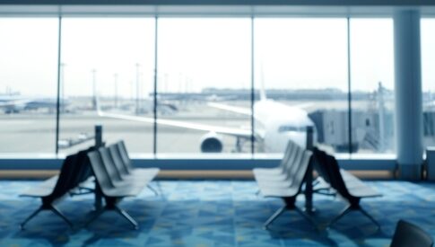 Blurred view of an airport terminal with seats and an airplane in the background