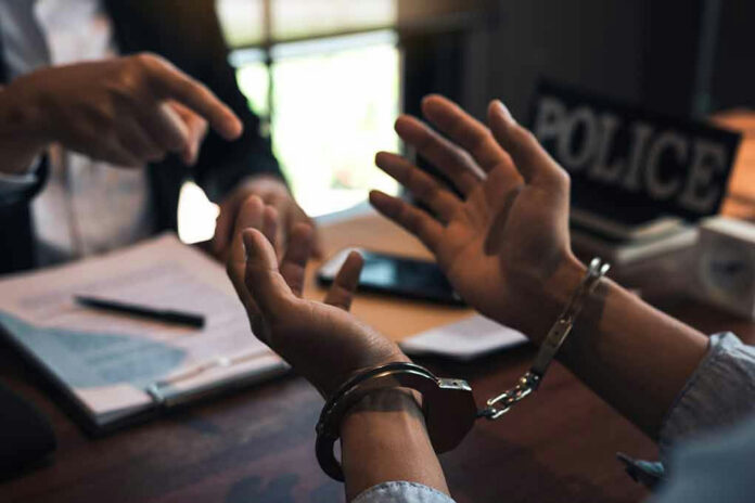 Handcuffed person is questioned by a police officer.
