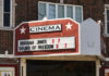 Cinema marquee on a brick building displaying current movie titles and showtimes