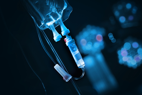 Intravenous,Drip,With,Solution,Bag,In,A,Dark,Room. Close-up of an IV drip setup with a blue background